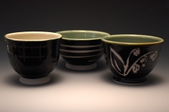 a trio of teabowls with various surface designs: spiral and lily of the valley in wax resist; aperture checkered motif in iron oxide resist