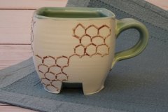 Small pseudocube mug: thrown then altered porcelain with celadon glaze and hexagonal lattice motif, cone 6 oxidation.