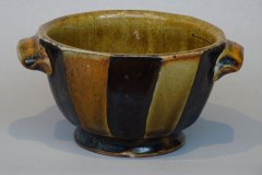 Stout striped bowl: amber glaze with black slip stripes, dual handles, trimmed foot.