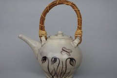 Prairie teapot: dense earthenware, rutile glaze with brushed flower designs and butterfly motif, natural vine handle.